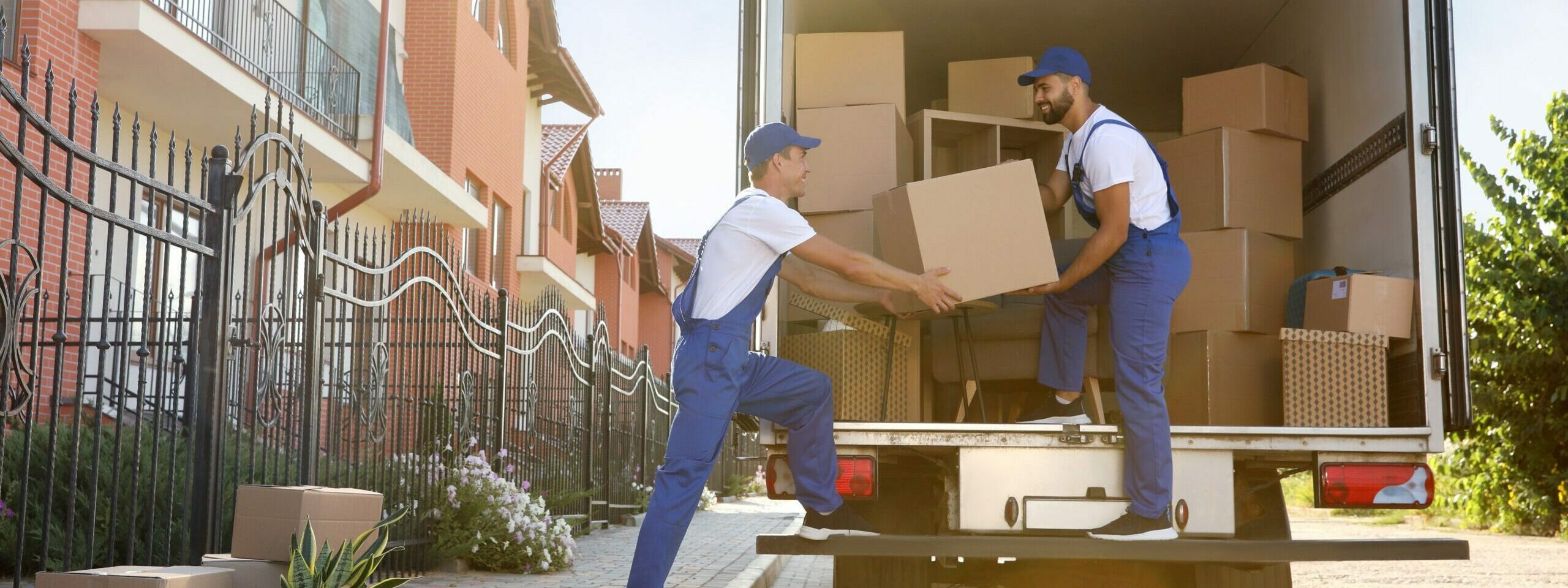 Workers unloading boxes from van outdoors. Moving service